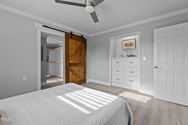 bedroom featuring hardwood / wood-style flooring, ornamental molding, a barn door, and ceiling fan