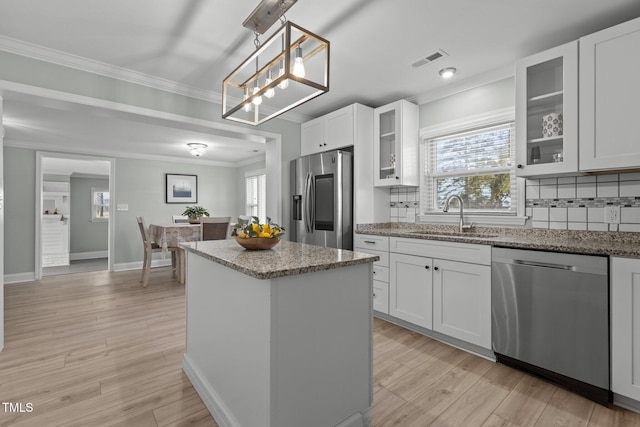 kitchen featuring appliances with stainless steel finishes, decorative light fixtures, tasteful backsplash, sink, and white cabinets