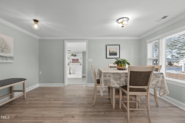 dining room featuring crown molding and light hardwood / wood-style floors