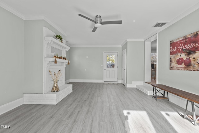 unfurnished living room featuring crown molding, ceiling fan, a fireplace, and light hardwood / wood-style floors