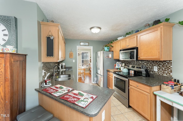 kitchen featuring sink, stainless steel appliances, tasteful backsplash, a textured ceiling, and light tile patterned floors