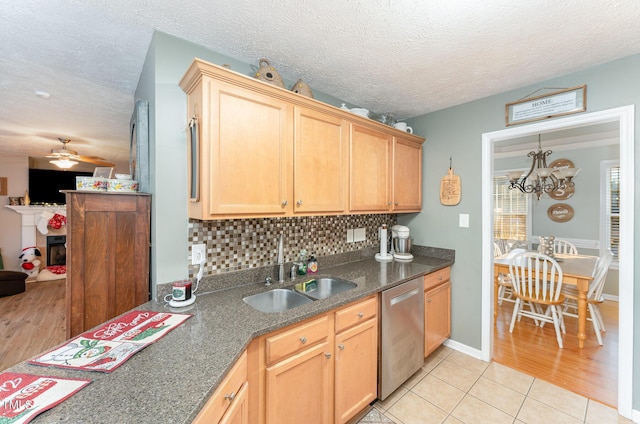 kitchen with dishwasher, sink, decorative backsplash, light tile patterned floors, and ceiling fan with notable chandelier