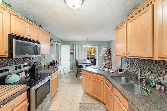 kitchen with backsplash, sink, hanging light fixtures, light tile patterned floors, and stainless steel appliances