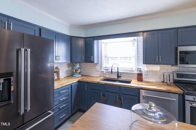 kitchen featuring blue cabinetry, appliances with stainless steel finishes, butcher block countertops, and sink