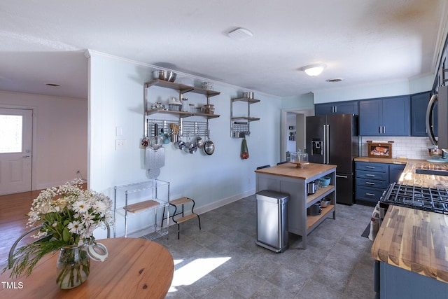 kitchen with butcher block countertops, high end fridge, blue cabinetry, and tasteful backsplash