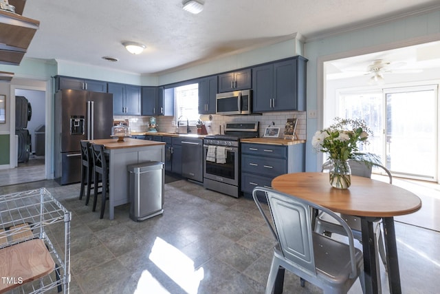 kitchen featuring butcher block counters, blue cabinets, and stainless steel appliances