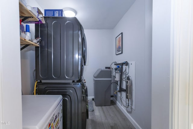 clothes washing area featuring stacked washer / dryer and dark wood-type flooring