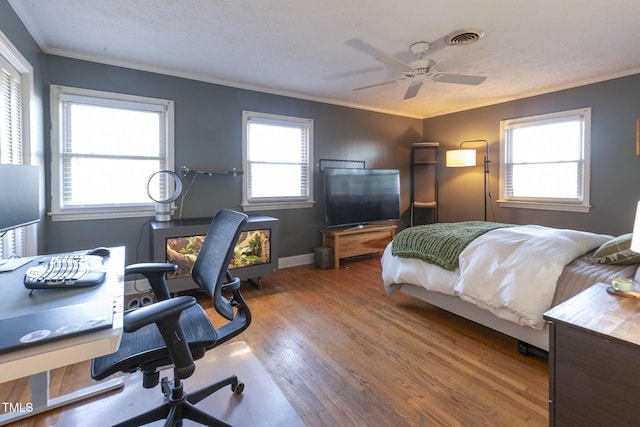 bedroom featuring multiple windows, ceiling fan, ornamental molding, and hardwood / wood-style flooring