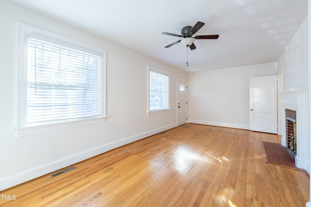 unfurnished living room with a brick fireplace, light hardwood / wood-style floors, and ceiling fan