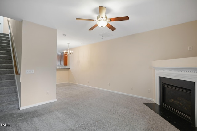 unfurnished living room featuring ceiling fan with notable chandelier and carpet floors