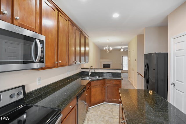 kitchen with black appliances, ceiling fan with notable chandelier, sink, hanging light fixtures, and dark stone countertops