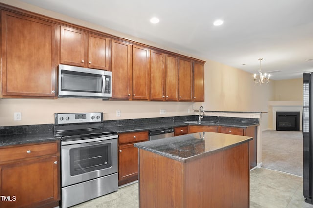 kitchen with sink, an inviting chandelier, decorative light fixtures, a kitchen island, and appliances with stainless steel finishes