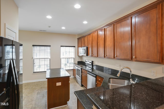 kitchen featuring dark stone counters, sink, a kitchen island, and stainless steel appliances