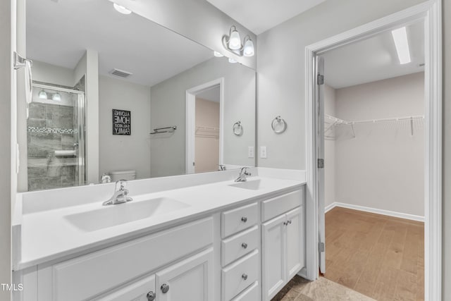 bathroom featuring wood-type flooring, vanity, toilet, and walk in shower