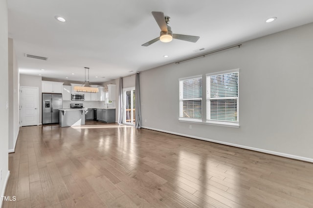 unfurnished living room featuring ceiling fan and wood-type flooring