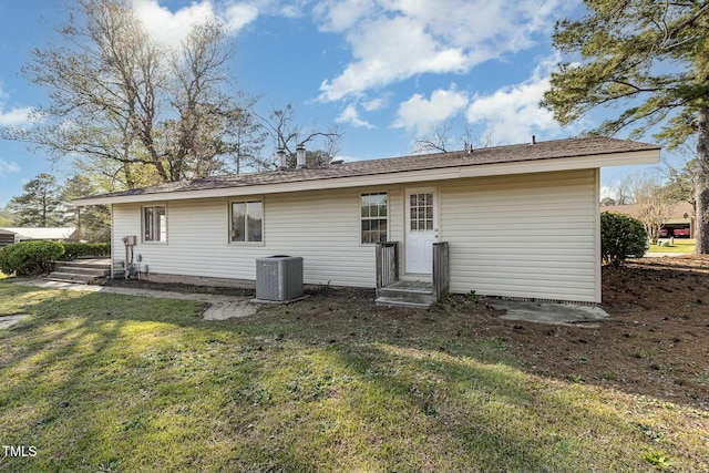 rear view of property with a lawn and cooling unit