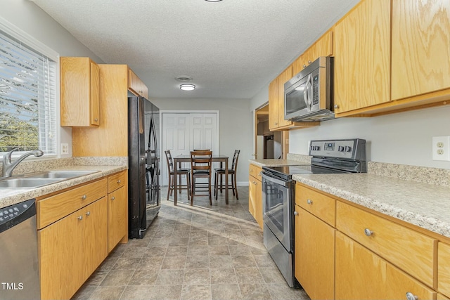 kitchen with sink, a textured ceiling, and appliances with stainless steel finishes