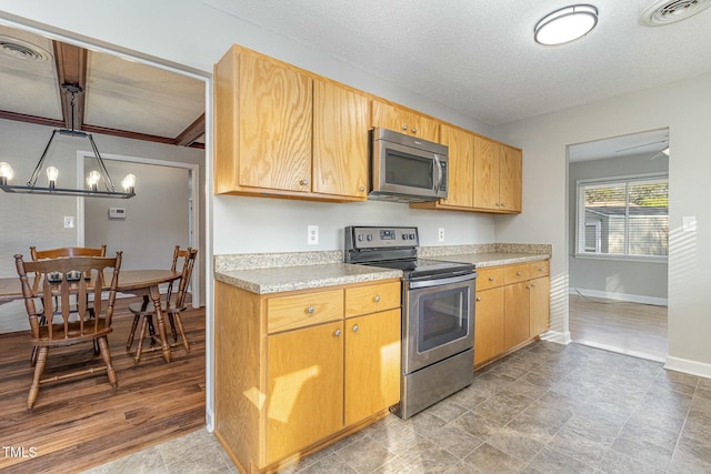 kitchen with a textured ceiling, a notable chandelier, and stainless steel appliances