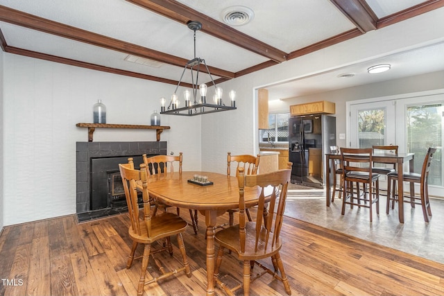 dining space featuring beam ceiling, a tile fireplace, and light hardwood / wood-style floors