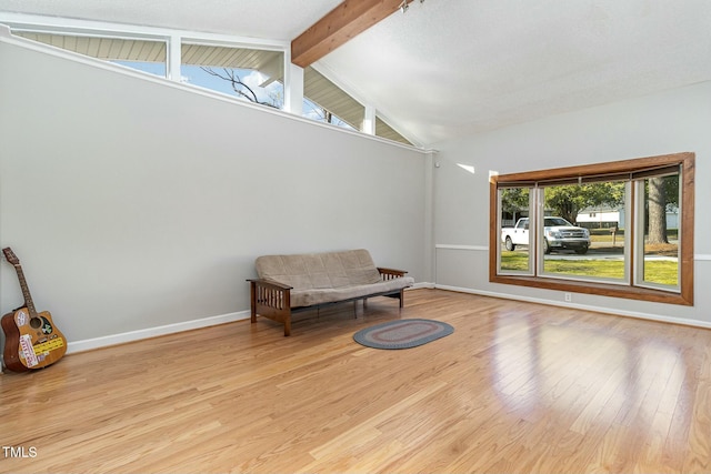 living area with lofted ceiling with beams, a wealth of natural light, and light hardwood / wood-style flooring