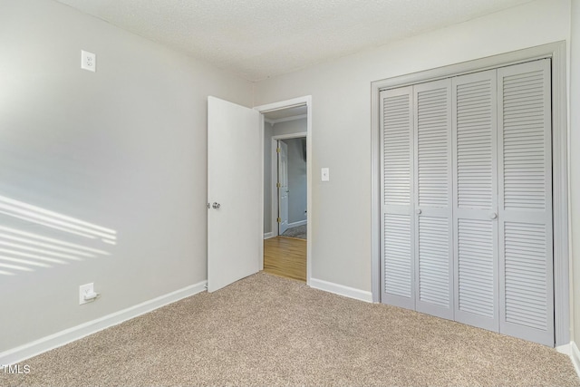 unfurnished bedroom featuring carpet, a textured ceiling, and a closet