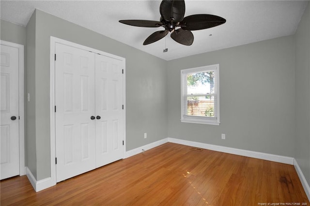 unfurnished bedroom with ceiling fan, wood-type flooring, and a closet