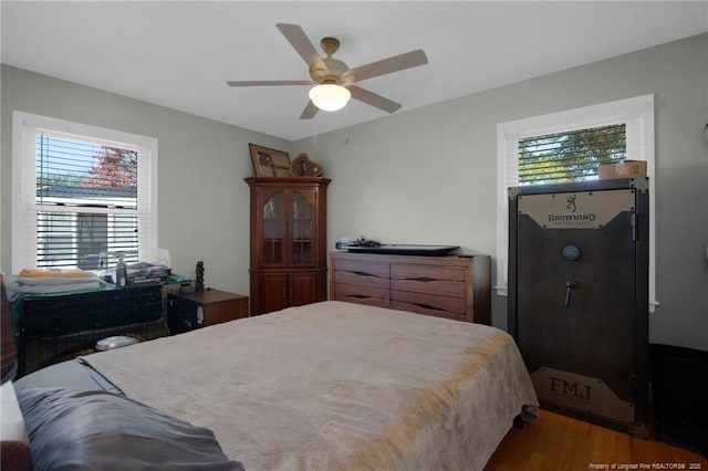 bedroom featuring hardwood / wood-style flooring, ceiling fan, and multiple windows