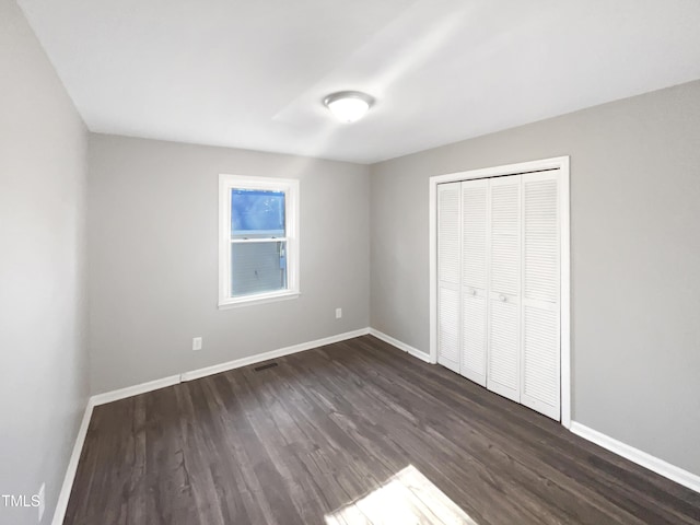 unfurnished bedroom featuring dark hardwood / wood-style flooring and a closet