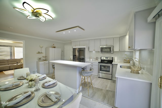 kitchen with a center island, a kitchen breakfast bar, sink, crown molding, and stainless steel appliances