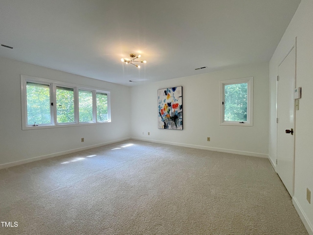 empty room featuring light carpet and a chandelier