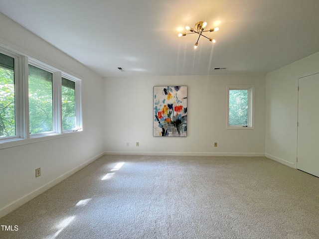 carpeted spare room with a wealth of natural light and a chandelier