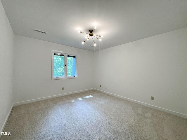 carpeted spare room featuring a notable chandelier