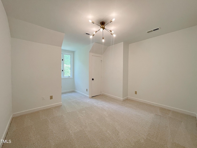 spare room with light colored carpet and a notable chandelier