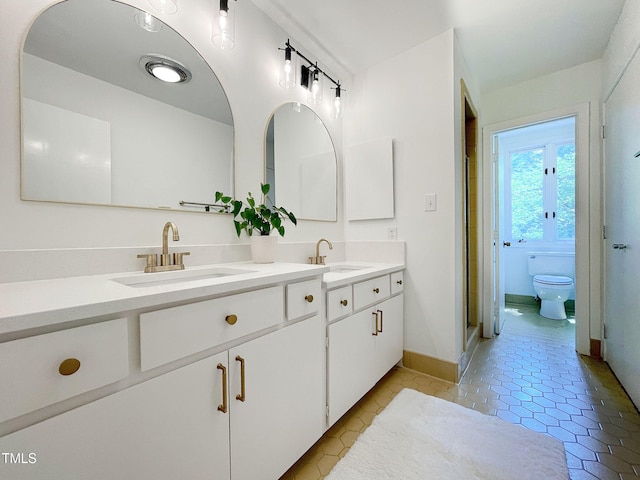 bathroom featuring toilet, tile patterned flooring, a shower with door, and vanity