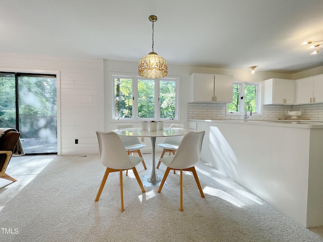 dining space with light colored carpet, a notable chandelier, and sink