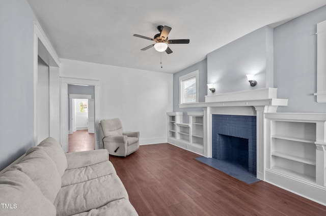 living room featuring ceiling fan, dark wood-type flooring, and a brick fireplace