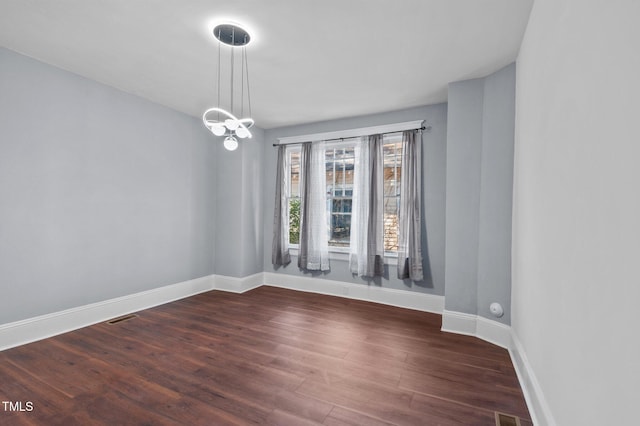 unfurnished room featuring dark wood-type flooring and a chandelier