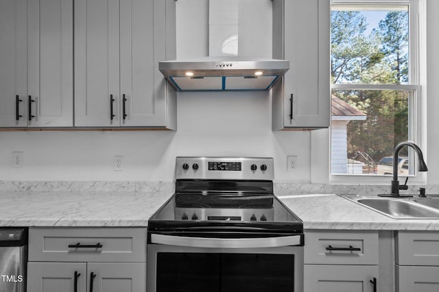 kitchen with light stone counters, sink, wall chimney range hood, and appliances with stainless steel finishes