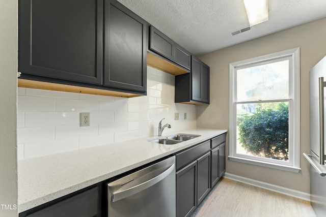 kitchen featuring stainless steel dishwasher, light hardwood / wood-style floors, light stone counters, and sink