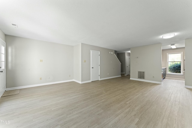 unfurnished living room featuring light hardwood / wood-style floors and a textured ceiling