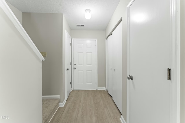 hall with light hardwood / wood-style floors and a textured ceiling