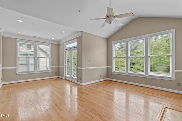 spare room featuring light hardwood / wood-style floors, vaulted ceiling, ceiling fan, and a healthy amount of sunlight