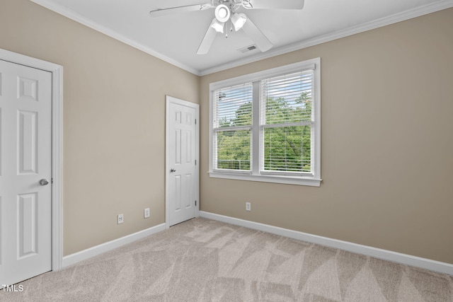 unfurnished bedroom featuring ceiling fan, light colored carpet, and crown molding