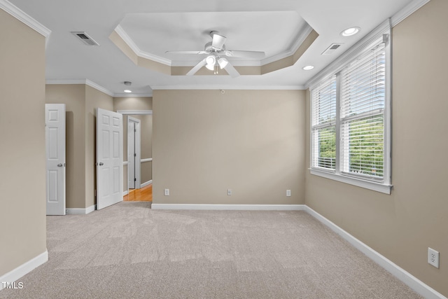 carpeted empty room featuring a raised ceiling, crown molding, and ceiling fan