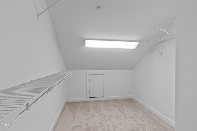 spacious closet with light colored carpet and vaulted ceiling