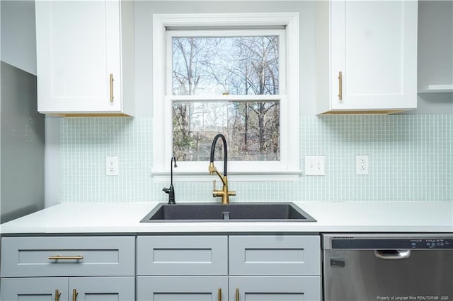 kitchen with backsplash, white cabinetry, dishwasher, and sink