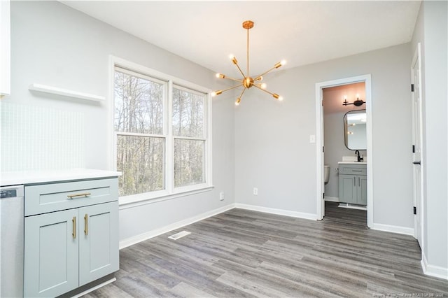 unfurnished dining area with wood-type flooring, an inviting chandelier, and a healthy amount of sunlight