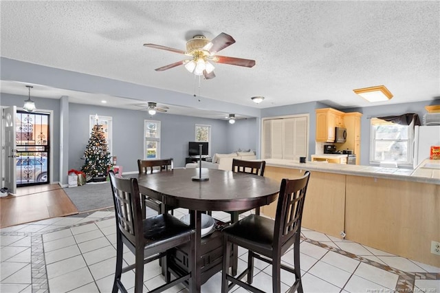 tiled dining room featuring a wealth of natural light, ceiling fan, and a textured ceiling