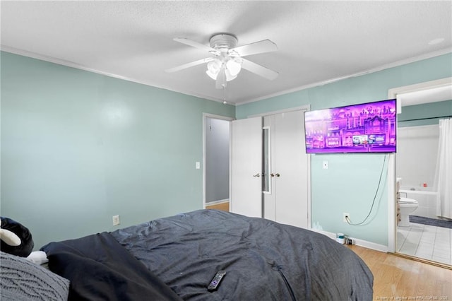 bedroom with connected bathroom, light hardwood / wood-style flooring, ceiling fan, and crown molding