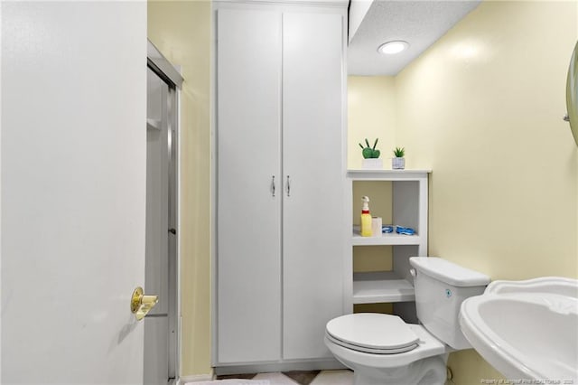 bathroom with sink, a textured ceiling, and toilet